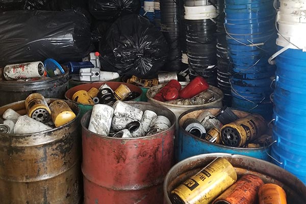 Large canisters filled with used oil filters and jugs